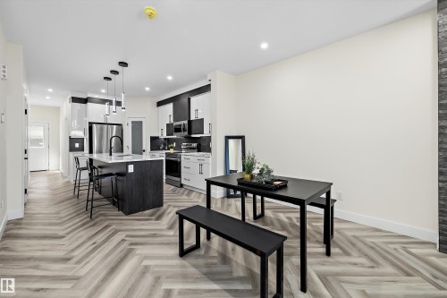 Modern kitchen featuring a central island with countertop seating, stainless steel appliances, and a black and white cabinetry scheme - 8319 81 Avenue Nw, Edmonton, AB 