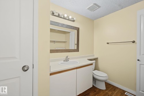 Bathroom vanity featuring a white countertop with an integrated sink, a large framed mirror, and a five-light fixture - 4259 29 Avenue, Edmonton, AB 