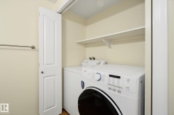 Dedicated laundry closet featuring a built-in shelf, white paneled bifold door, and wood-finish flooring - 