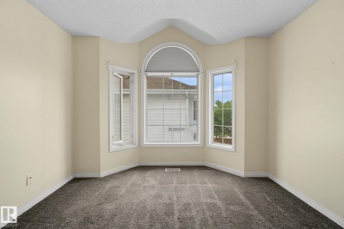 Bay window with an arched transom window, neutral-toned walls, textured ceiling, and gray patterned carpet - 4259 29 Avenue, Edmonton, AB 