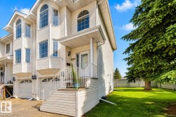 Multi-level townhome featuring white siding, multiple arched windows, and a covered front entry - 