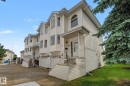 Multi-level townhouse exterior featuring white siding, multiple bay windows with arched transoms, and an integrated single-car garage - 4259 29 Avenue, Edmonton, AB 