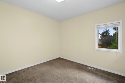 Neutral tone wall finishes, dark textured carpet, and a single window with white trim - 