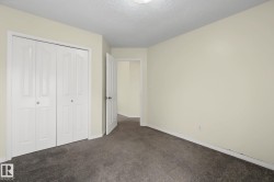 Neutral-toned room featuring a textured ceiling, dark gray carpet, and a white bi-fold closet with panel details - 