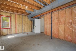 Unfinished basement featuring exposed wood joists, concrete flooring, and insulated walls - 