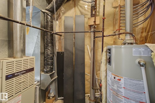 Mechanical room featuring a water heater, furnace unit, and extensive ductwork - 4259 29 Avenue, Edmonton, AB 