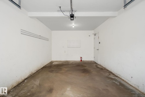 Spacious garage featuring a concrete floor, painted white walls, and a ceiling-mounted garage door opener - 4259 29 Avenue, Edmonton, AB 