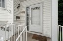 White vinyl siding exterior featuring an entryway with a storm door, an outdoor wall lantern, a wall-mounted mailbox, and white porch railings - 4259 29 Avenue, Edmonton, AB 