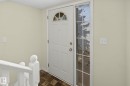 Entryway featuring a paneled door with an arched window, a full-length side window, a white painted railing, and patterned floor tile - 4259 29 Avenue Nw, Edmonton, AB  - Indoor Photo Showing Other Room 