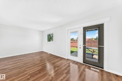 Spacious room featuring wood-finish flooring and white walls - 
