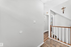 Foyer featuring tile flooring, painted walls, and wood-finish railing with white spindles - 