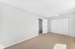 Bedroom featuring light neutral wall paint, white baseboards, a textured ceiling, flush-mount lighting, and beige carpeting - 