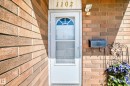 Brick exterior featuring a white entry door with an arched window, a wall-mounted mailbox, and an exterior light fixture - 1102 Millbourne Road E, Edmonton, AB 