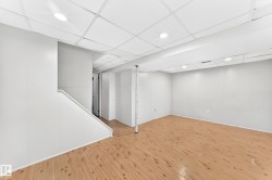 Open-concept finished basement with wood-finish flooring, white paneling, drop ceiling, and recessed lighting - 