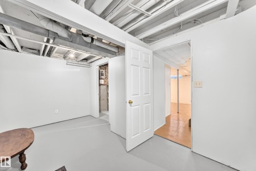 Unfinished basement space featuring exposed ceiling joists and ductwork, painted white walls, and a light gray finished concrete floor - 1102 Millbourne Road E, Edmonton, AB 