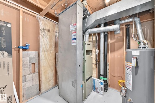 Utility area featuring a furnace, water heater, exposed wood framing, and white painted concrete floor - 1102 Millbourne Road E, Edmonton, AB 
