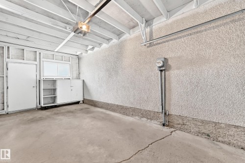 Interior garage space with exposed white-painted ceiling joists, textured walls, and a concrete floor - 1102 Millbourne Road E, Edmonton, AB 