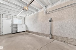 Interior garage space with exposed white-painted ceiling joists, textured walls, and a concrete floor - 