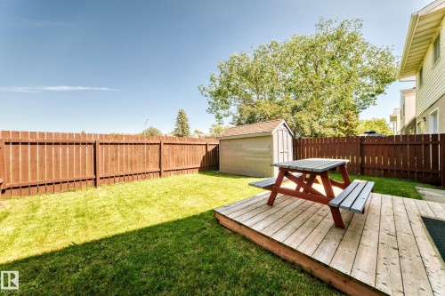 Expansive backyard featuring a manicured lawn, a low-profile wood-finish deck, and a privacy fence - 1102 Millbourne Road E, Edmonton, AB 