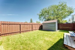 Expansive grassy yard with a privacy fence, wood-finish deck, and storage shed - 