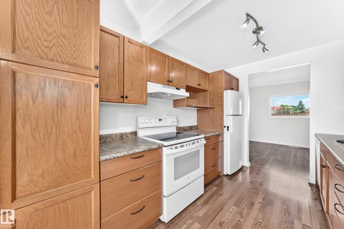Kitchen featuring wood cabinetry, white appliances, laminate countertops, and wood-finish flooring - 1102 Millbourne Road E, Edmonton, AB 