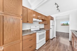 Kitchen featuring wood cabinetry, white appliances, laminate countertops, and wood-finish flooring - 
