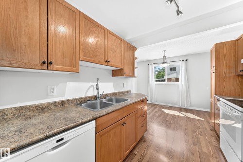 Kitchen featuring wood-finish cabinetry, a double basin stainless steel sink, and a dishwasher - 1102 Millbourne Road E, Edmonton, AB 