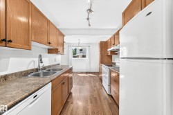Kitchen featuring wood-finish cabinetry, laminate countertops, a double basin stainless steel sink with chrome faucet, and white appliances including a refrigerator, range, and dishwasher - 