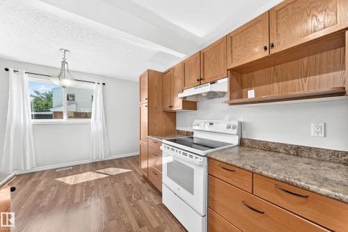 Kitchen featuring wood-finish cabinetry, a freestanding electric range, and laminate countertops - 1102 Millbourne Road E, Edmonton, AB 