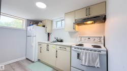 Compact kitchen area featuring neutral cabinetry, a white refrigerator, a white electric range, and a stainless steel sink - 