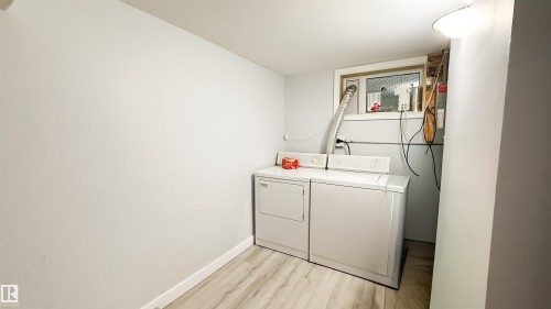 Dedicated laundry area with light wood-finish flooring, a window, and white painted walls - 12005 40 St, Edmonton, AB 