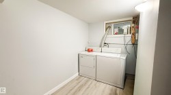 Dedicated laundry area with light wood-finish flooring, a window, and white painted walls - 