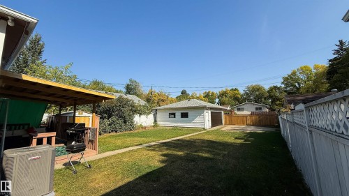 Expansive backyard featuring a covered patio, detached garage, grassy lawn, and perimeter fencing - 12005 40 St, Edmonton, AB 