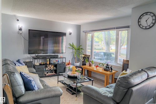 Living area featuring light gray walls, wood-finish flooring, recessed lighting, and a large bay window - 12005 40 St, Edmonton, AB 
