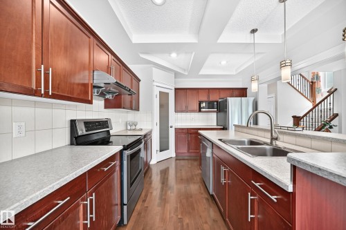 Kitchen featuring wood-finish cabinetry, light-toned countertops, and wood-finish flooring - 1330 114B Street, Edmonton, AB 