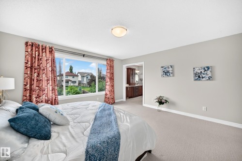 Spacious room featuring broad windows with exterior views, light-toned carpeting, and an entryway to an additional interior space with wood-finish cabinetry - 1330 114B Street, Edmonton, AB 