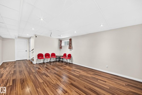 Spacious room featuring wood-finish flooring, light neutral wall paint, and a white panel ceiling with recessed lighting - 1330 114B Street, Edmonton, AB 
