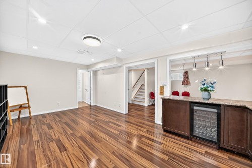 Spacious lower level featuring wood-finish flooring, recessed lighting, and a built-in wet bar with a beverage cooler and granite-style countertop - 1330 114B Street, Edmonton, AB 