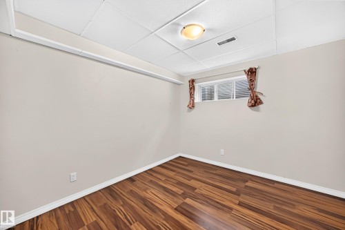 Room featuring wood-finish flooring, a neutral wall palette, and white baseboards - 1330 114B Street, Edmonton, AB 