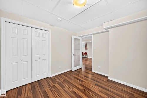 Interior room featuring wood-finish flooring, light neutral-toned walls, and a drop ceiling - 1330 114B Street, Edmonton, AB 