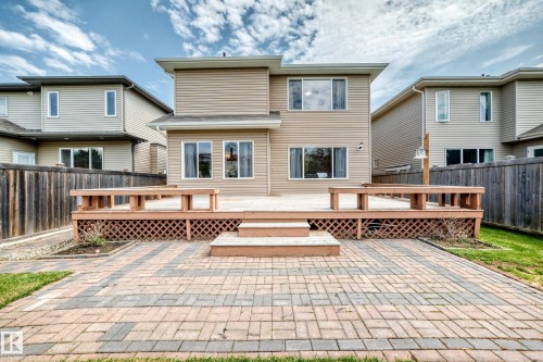 Spacious outdoor living area featuring a multi-level wooden deck with integrated benches, a patterned brick patio, and a privacy fence - 1330 114B Street, Edmonton, AB 