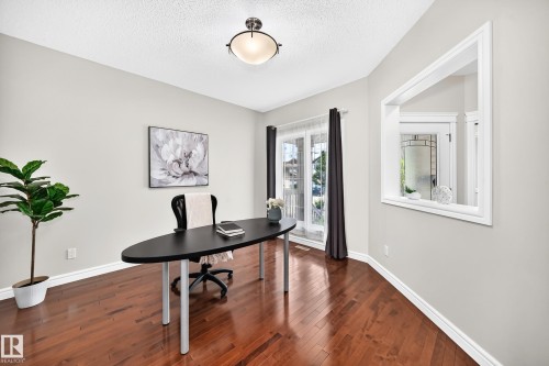 Hardwood flooring throughout this room, featuring light gray walls, white baseboards, and a semi-flush mount ceiling fixture - 1330 114B Street, Edmonton, AB 