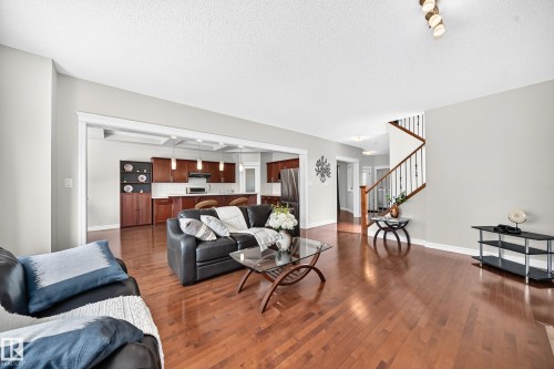 Spacious living area featuring rich wood-finish flooring, light grey wall tones, and an open transition to the kitchen - 1330 114B Street, Edmonton, AB 