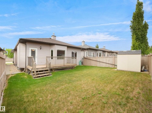 Backyard featuring a wooden deck with steps, a detached storage shed, and perimeter fencing - 45 Willow Wood Lane, Stony Plain, AB 