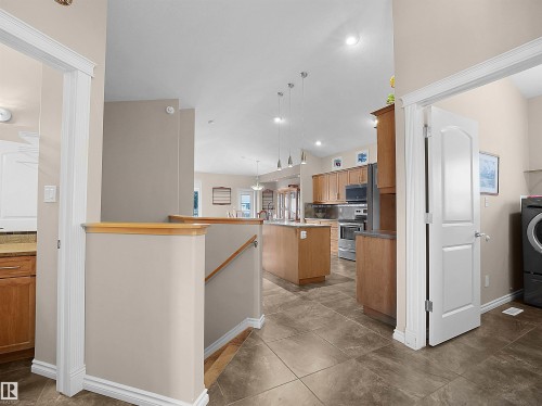 Tiled entryway featuring a descending staircase with wood railing, recessed lighting, and a white interior door - 45 Willow Wood Lane, Stony Plain, AB 