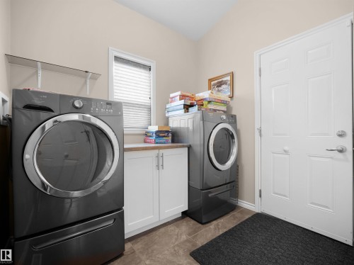 Laundry area with vaulted ceiling, white paneled door, and a single window with blinds - 45 Willow Wood Lane, Stony Plain, AB 