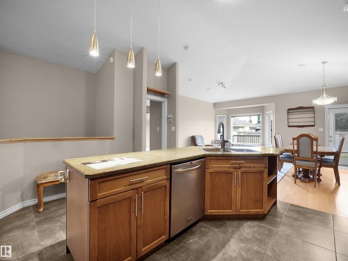 Kitchen island featuring wood cabinetry, stone-look countertop, and a built-in stainless steel dishwasher - 45 Willow Wood Lane, Stony Plain, AB 