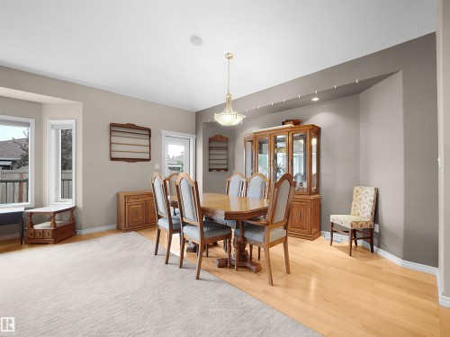 Dining area featuring wood-finish flooring, a contemporary chandelier, recessed lighting, and bay windows - 45 Willow Wood Lane, Stony Plain, AB 