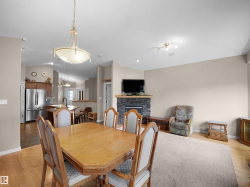 Open-concept living area with a vaulted ceiling and a prominent fireplace featuring a stone surround and wood mantel - 45 Willow Wood Lane, Stony Plain, AB 