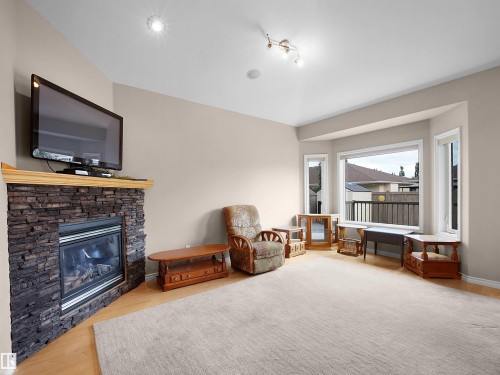 Living area featuring a corner fireplace with stone veneer surround and wood mantel - 45 Willow Wood Lane, Stony Plain, AB 
